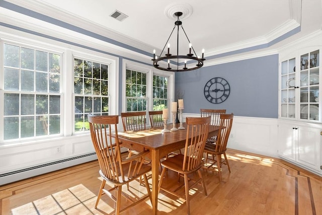 dining space featuring ornamental molding, light hardwood / wood-style flooring, and a notable chandelier