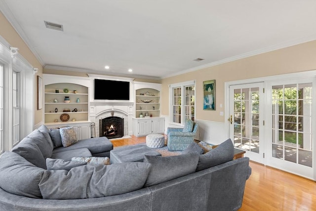 living room with hardwood / wood-style floors, crown molding, and built in features