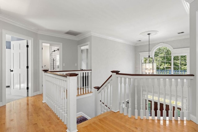 corridor with ornamental molding, wood-type flooring, and an inviting chandelier