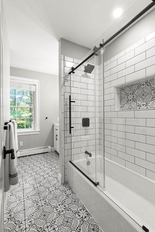 bathroom featuring a baseboard radiator, vanity, and enclosed tub / shower combo