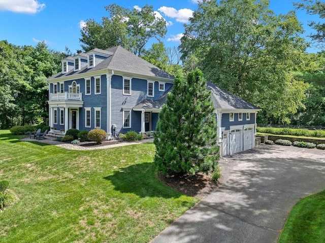 view of front of property featuring a balcony, a garage, and a front yard