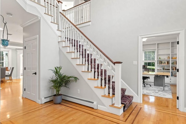 stairway with hardwood / wood-style floors, ornamental molding, and baseboard heating