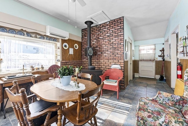 dining area with a wood stove, wood walls, stone finish floor, and a wall mounted AC