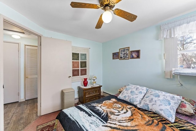 bedroom featuring a ceiling fan, a baseboard radiator, and wood finished floors