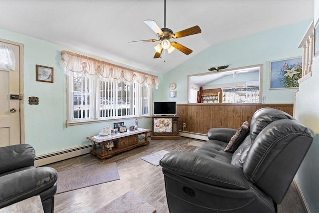 living room featuring a baseboard heating unit, vaulted ceiling, and a wainscoted wall