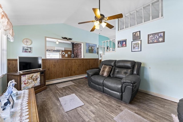 living area featuring lofted ceiling, baseboard heating, dark wood-type flooring, wainscoting, and wood walls