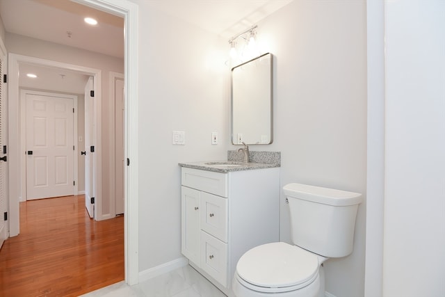 bathroom with vanity, toilet, and hardwood / wood-style flooring