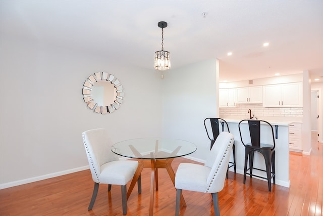 dining space with a notable chandelier, light hardwood / wood-style floors, and sink