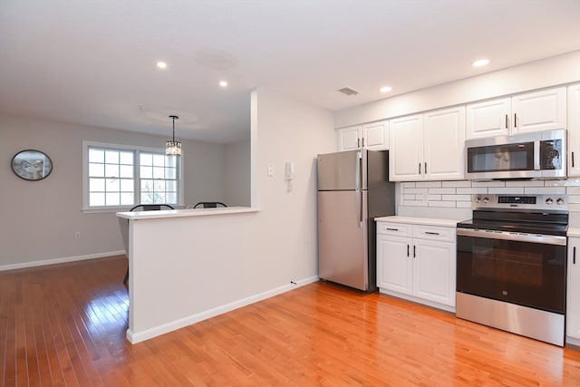 kitchen featuring appliances with stainless steel finishes, decorative backsplash, white cabinets, light hardwood / wood-style flooring, and decorative light fixtures