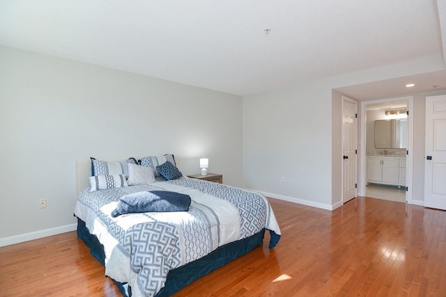 bedroom with connected bathroom and light hardwood / wood-style flooring