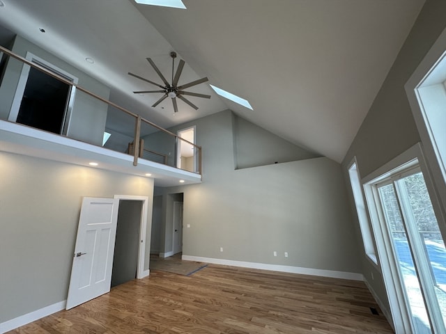 spare room with a skylight, ceiling fan, hardwood / wood-style floors, and high vaulted ceiling