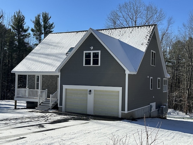 view of front of home featuring a porch, cooling unit, and a garage