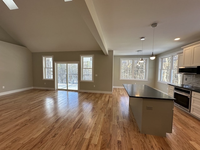 kitchen featuring stainless steel appliances, decorative light fixtures, light hardwood / wood-style flooring, white cabinets, and a center island