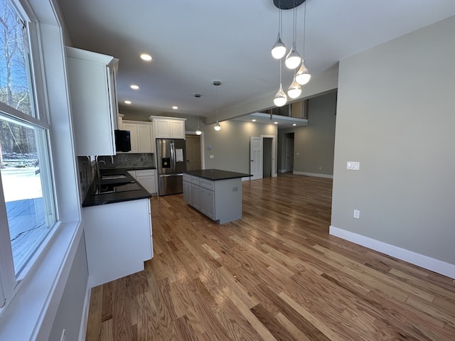 kitchen with sink, white cabinets, stainless steel fridge with ice dispenser, a kitchen island, and hanging light fixtures