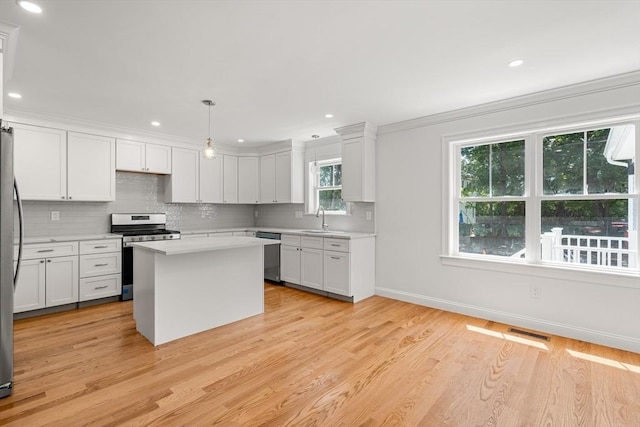 13 River Unit 2, Danvers, MA 01923 - kitchen with appliances with stainless steel finishes, light countertops, decorative backsplash, light wood-style floors, and white cabinetry