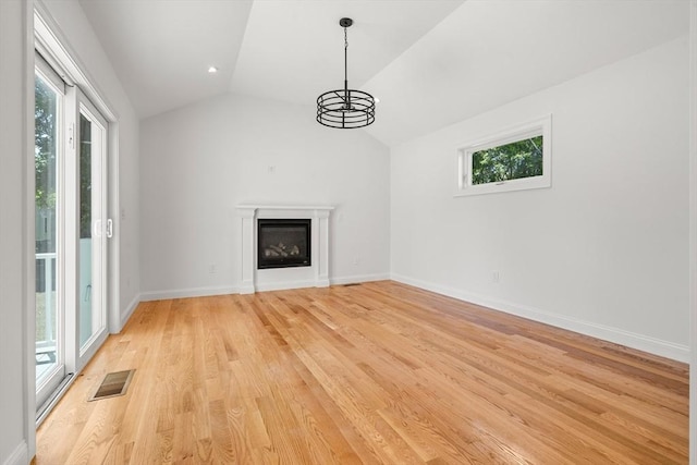 13 River Unit 2, Danvers, MA 01923 - unfurnished living room featuring healthy amount of natural light, lofted ceiling, light wood-type flooring, a chandelier, and a glass covered fireplace