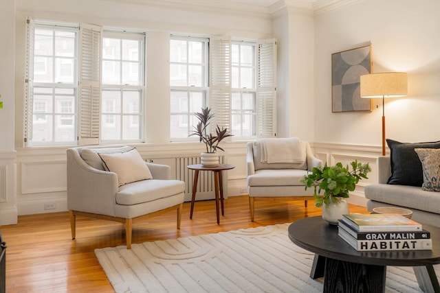 living room featuring radiator, light hardwood / wood-style flooring, crown molding, and a wealth of natural light