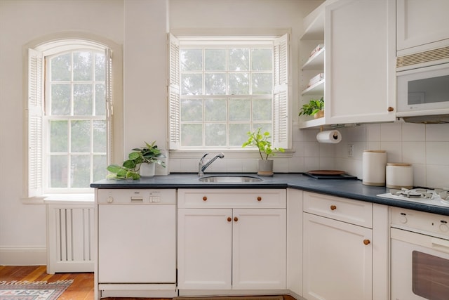 kitchen featuring white cabinets, sink, white appliances, tasteful backsplash, and light hardwood / wood-style flooring