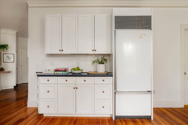 kitchen with decorative backsplash, light hardwood / wood-style floors, white cabinets, crown molding, and built in fridge