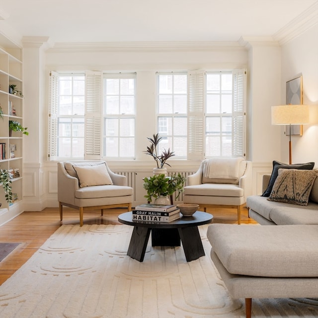 living room featuring wood-type flooring, built in shelves, and crown molding