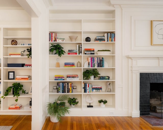 interior space with hardwood / wood-style flooring, built in features, and a brick fireplace