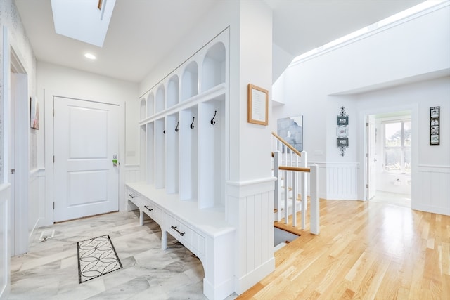 mudroom with a skylight and light hardwood / wood-style flooring