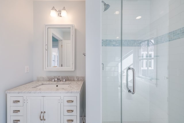 bathroom featuring a shower with door and vanity