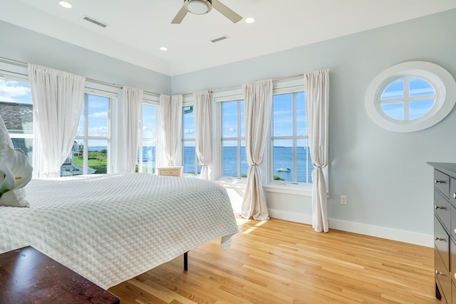 bedroom featuring a water view, multiple windows, and ceiling fan