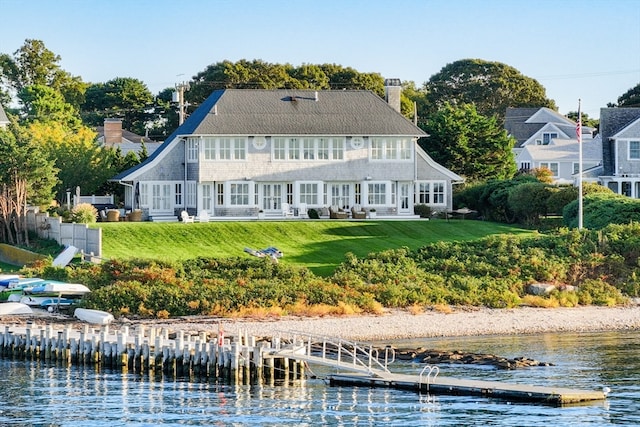 back of house with a lawn and a water view