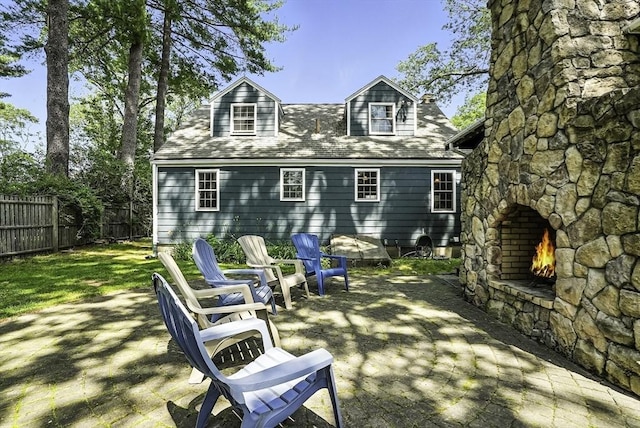 7 Vermont Ave, Natick, MA 01760 - back of property featuring an outdoor stone fireplace, a patio area, and a shingled roof