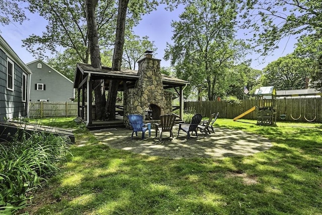 7 Vermont Ave, Natick, MA 01760 - fenced backyard featuring an outdoor stone fireplace, a patio, and a playground