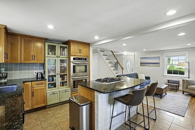 7 Vermont Ave, Natick, MA 01760 - kitchen featuring stainless steel appliances, open floor plan, a breakfast bar, brown cabinetry, and tasteful backsplash