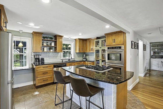7 Vermont Ave, Natick, MA 01760 - kitchen featuring appliances with stainless steel finishes, open shelves, brown cabinets, backsplash, and a breakfast bar area