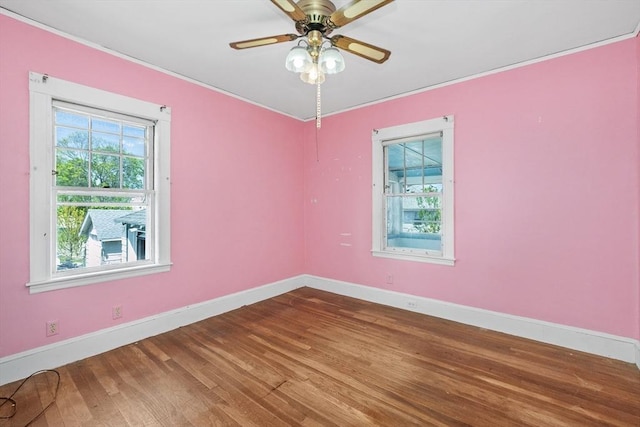 empty room with baseboards, ornamental molding, and wood finished floors