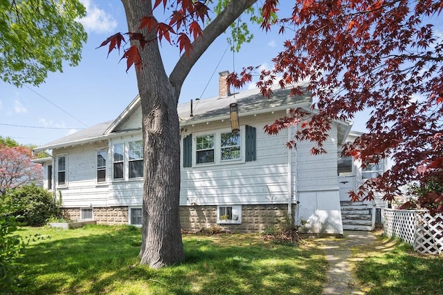 view of side of home with a lawn, fence, and a chimney