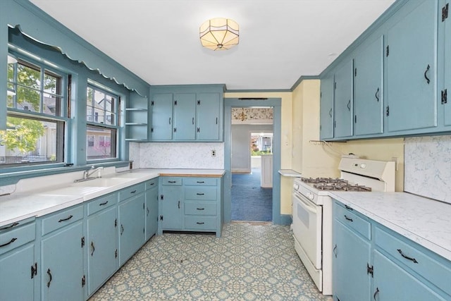kitchen featuring white gas stove, a wealth of natural light, a sink, and open shelves