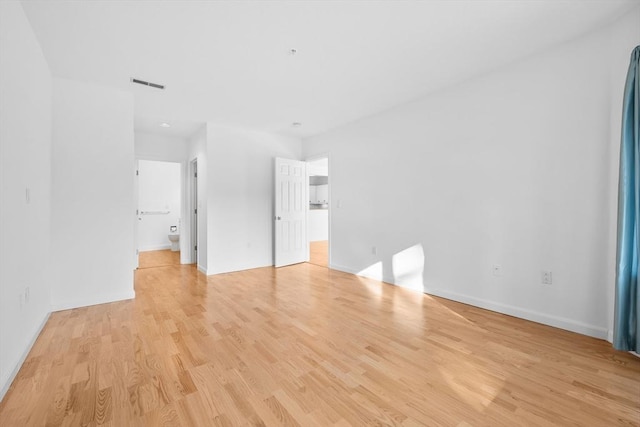 unfurnished bedroom featuring ensuite bathroom and light hardwood / wood-style floors