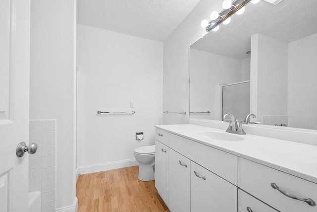 bathroom featuring vanity, hardwood / wood-style flooring, toilet, and walk in shower