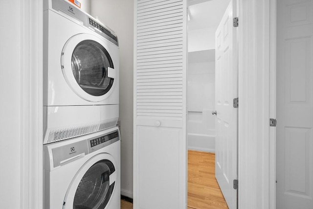 laundry room featuring hardwood / wood-style floors and stacked washer / drying machine