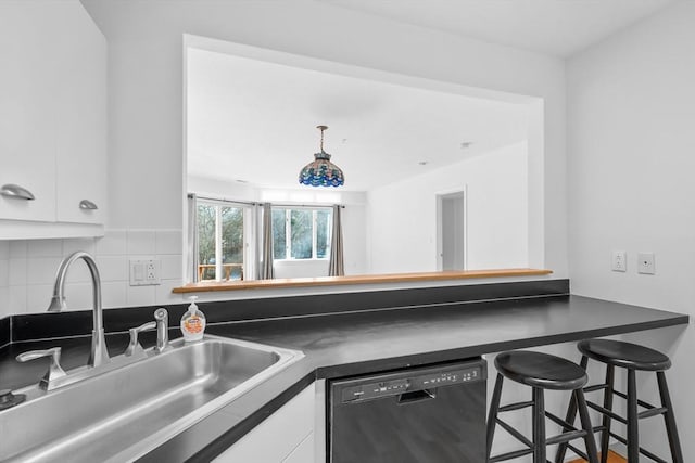 kitchen featuring white cabinetry, sink, black dishwasher, a kitchen bar, and decorative backsplash