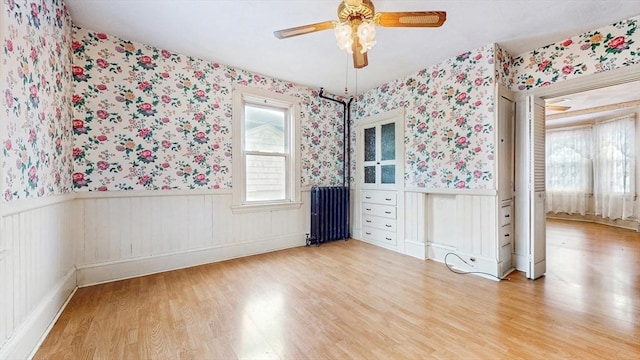 11 Quincy Ave, Norwood, MA 02062 - empty room featuring radiator, wallpapered walls, a wainscoted wall, ceiling fan, and wood finished floors