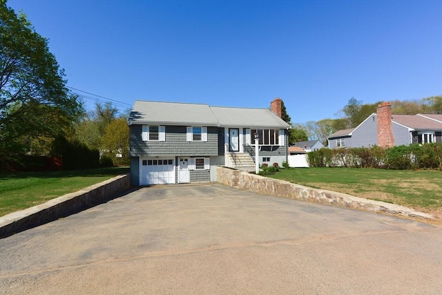 split foyer home with a chimney, aphalt driveway, and a front lawn