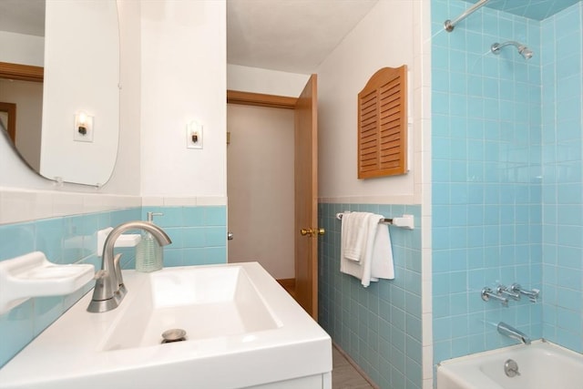 bathroom with tile walls, wainscoting, shower / bath combination, and a sink
