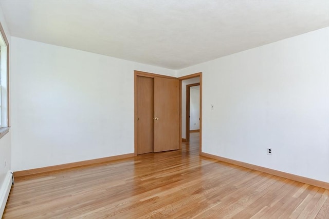 empty room featuring light wood finished floors and baseboards
