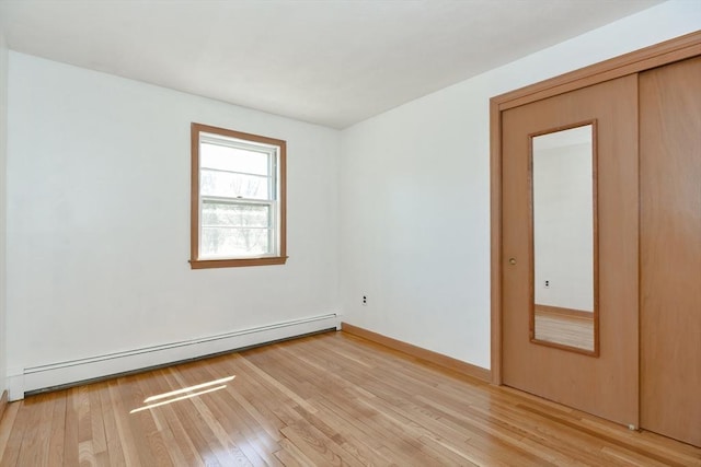 empty room featuring baseboards, baseboard heating, and light wood-style flooring