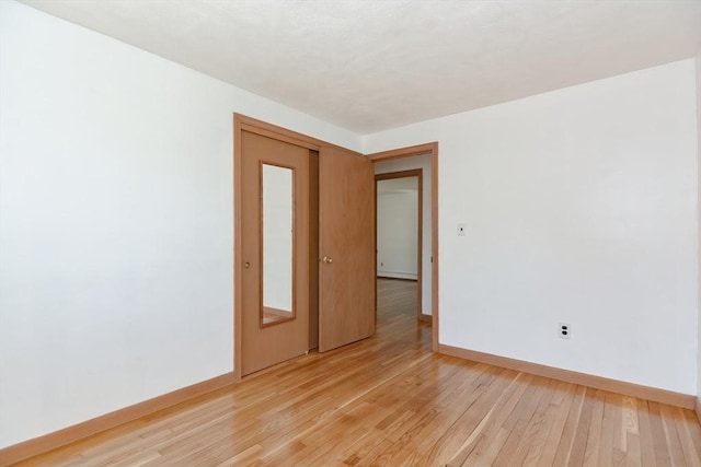 empty room with baseboards and light wood-style flooring
