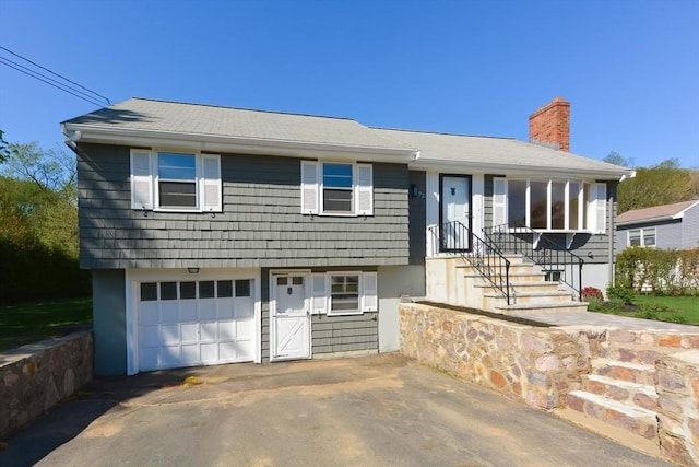 view of front facade featuring driveway, a chimney, and a garage