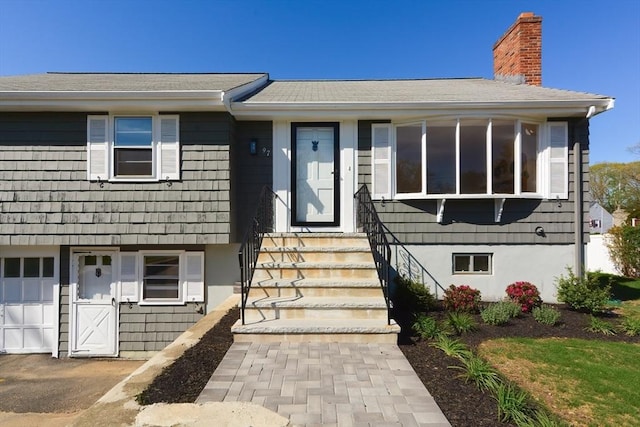 view of front of home featuring a chimney, entry steps, and a shingled roof
