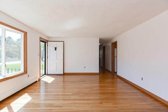 empty room with baseboards, baseboard heating, and light wood-style floors