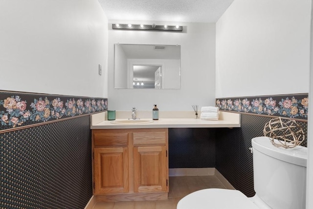 bathroom featuring tile patterned flooring, vanity, a textured ceiling, and toilet